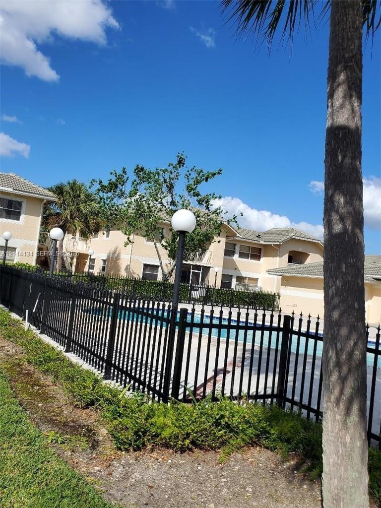 Swimming pool area featuring a perimeter black metal fence, integrated pole lighting, and manicured landscaping