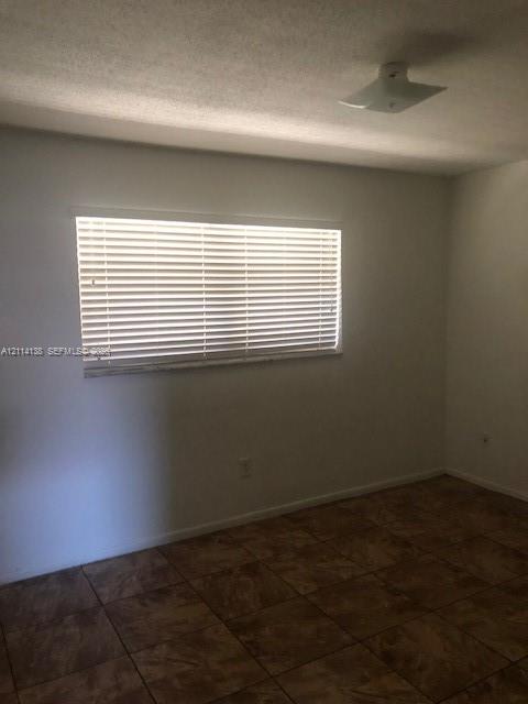 Interior room featuring neutral wall finishes, tile flooring, horizontal window blinds, and a flush-mount ceiling light fixture Interior room featuring neutral wall finishes, tile flooring, horizontal window blinds, and a flush-mount ceiling light fixture