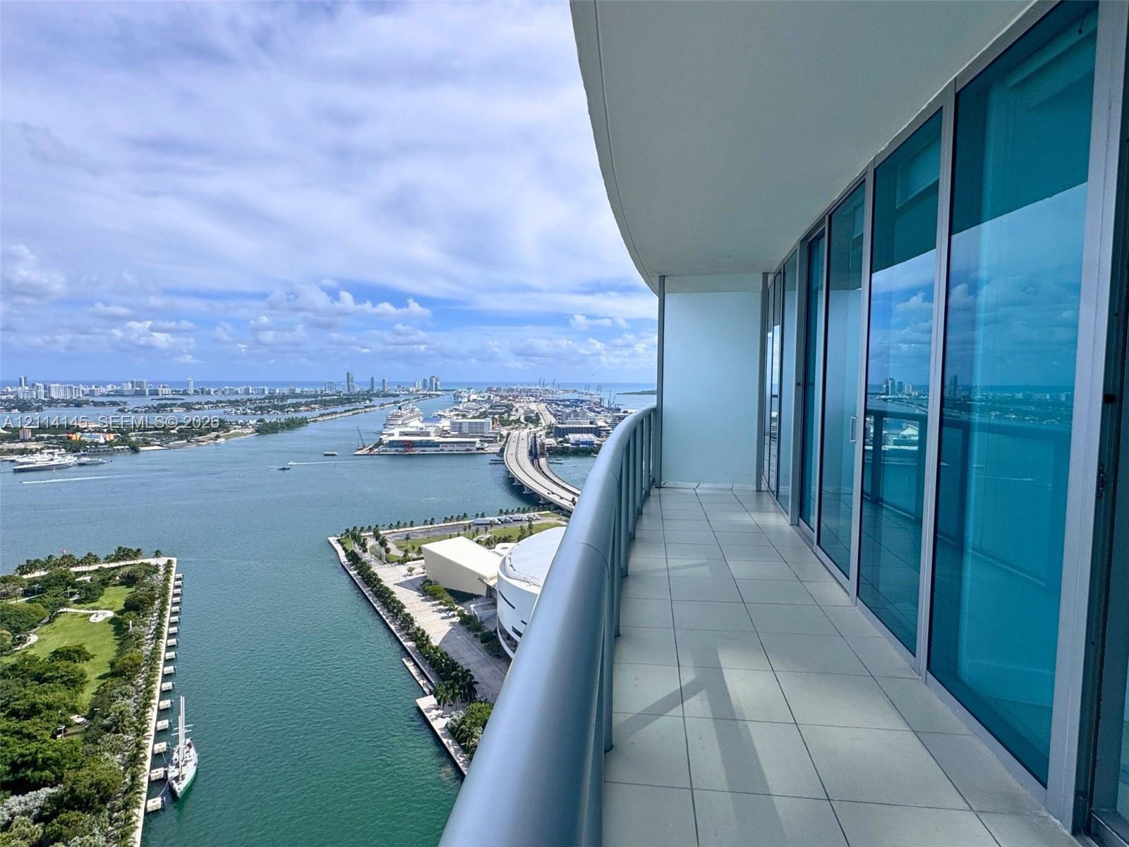 Curved balcony featuring large-format ceramic tile flooring, a metal railing, and floor-to-ceiling glass paneling