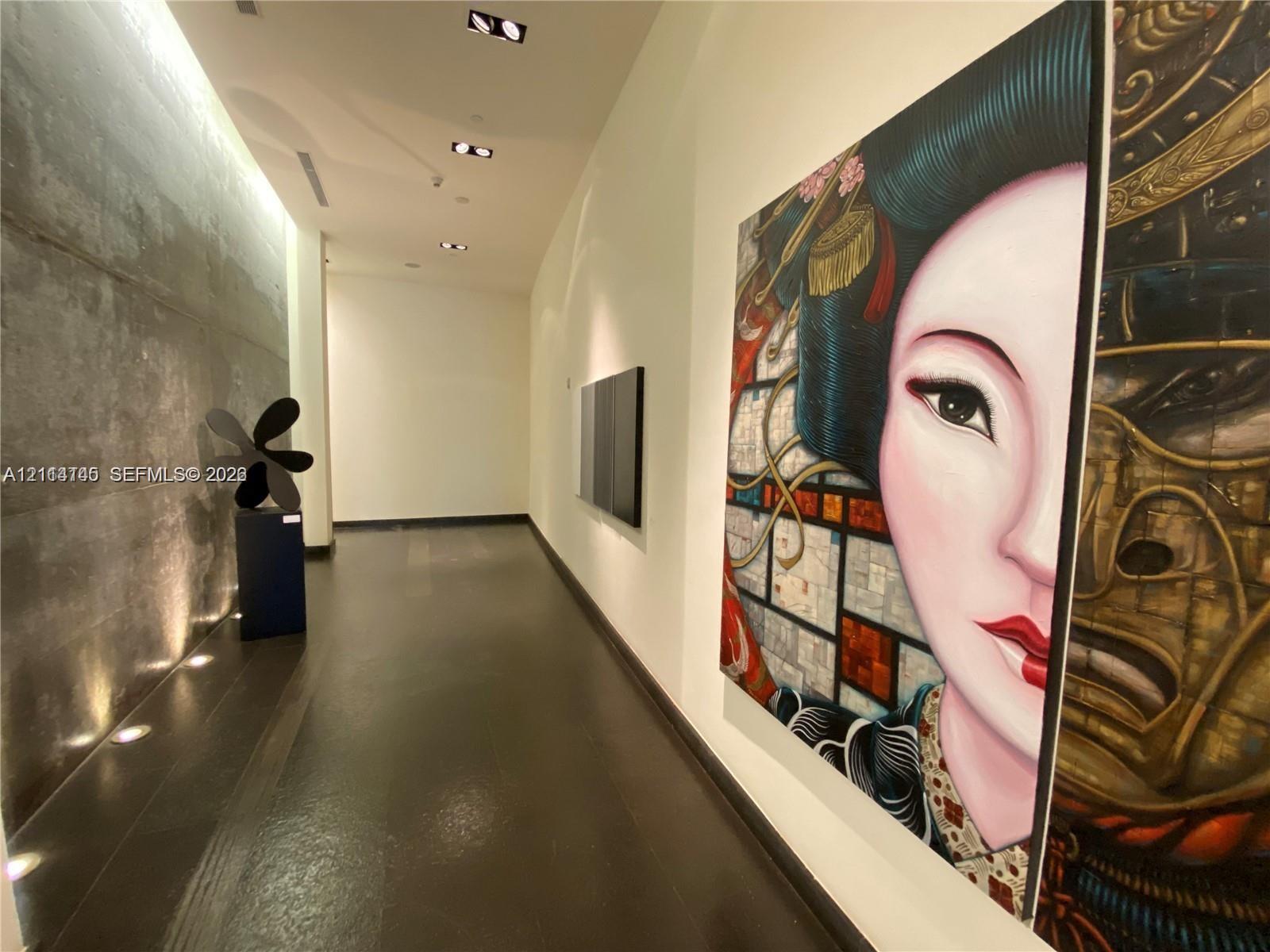 Gallery hallway featuring smooth concrete wall paneling, polished dark flooring, recessed ceiling lighting, and linear floor-level accent illumination