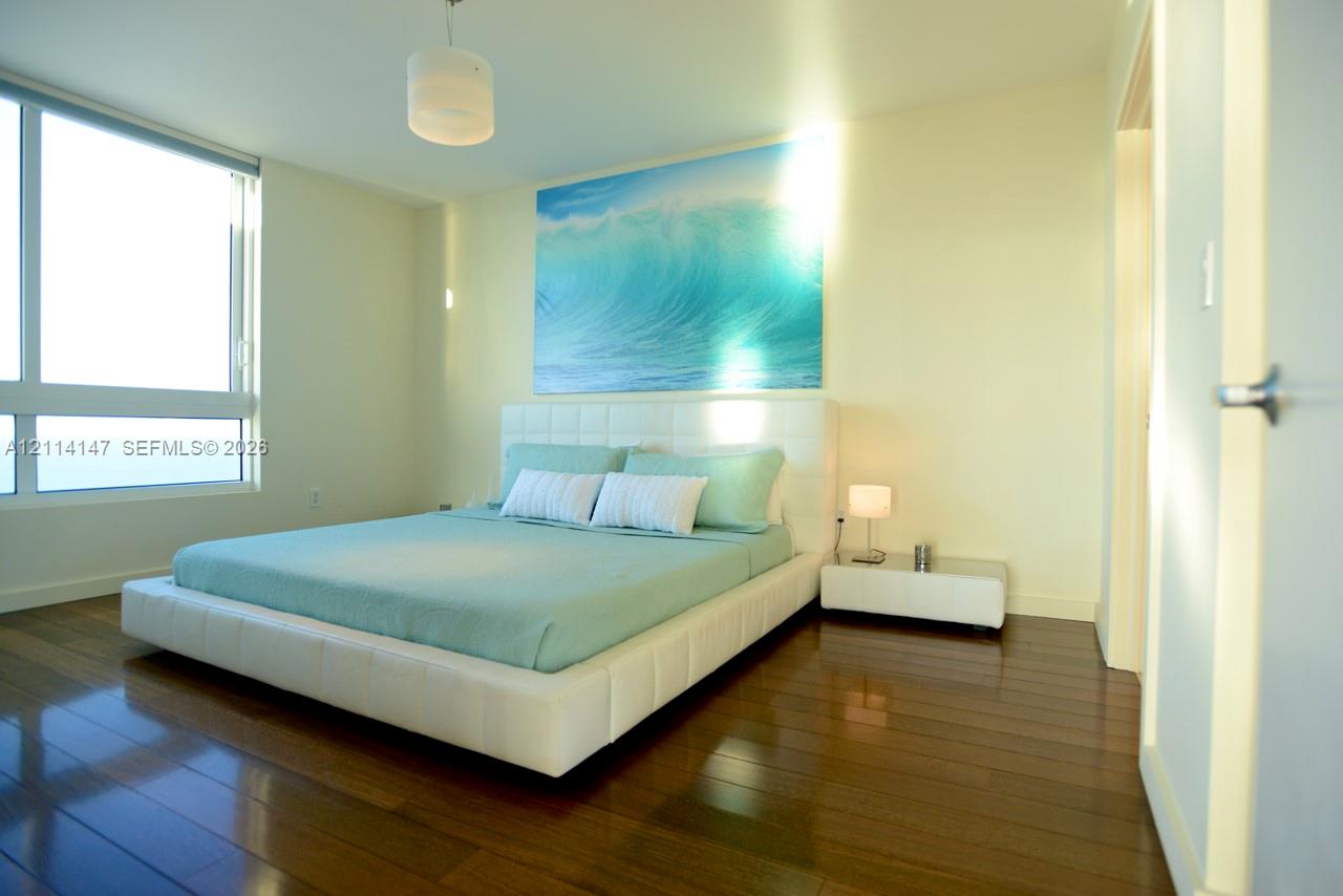 Floor-to-ceiling windows, wood-finish flooring, and a minimalist pendant light fixture
