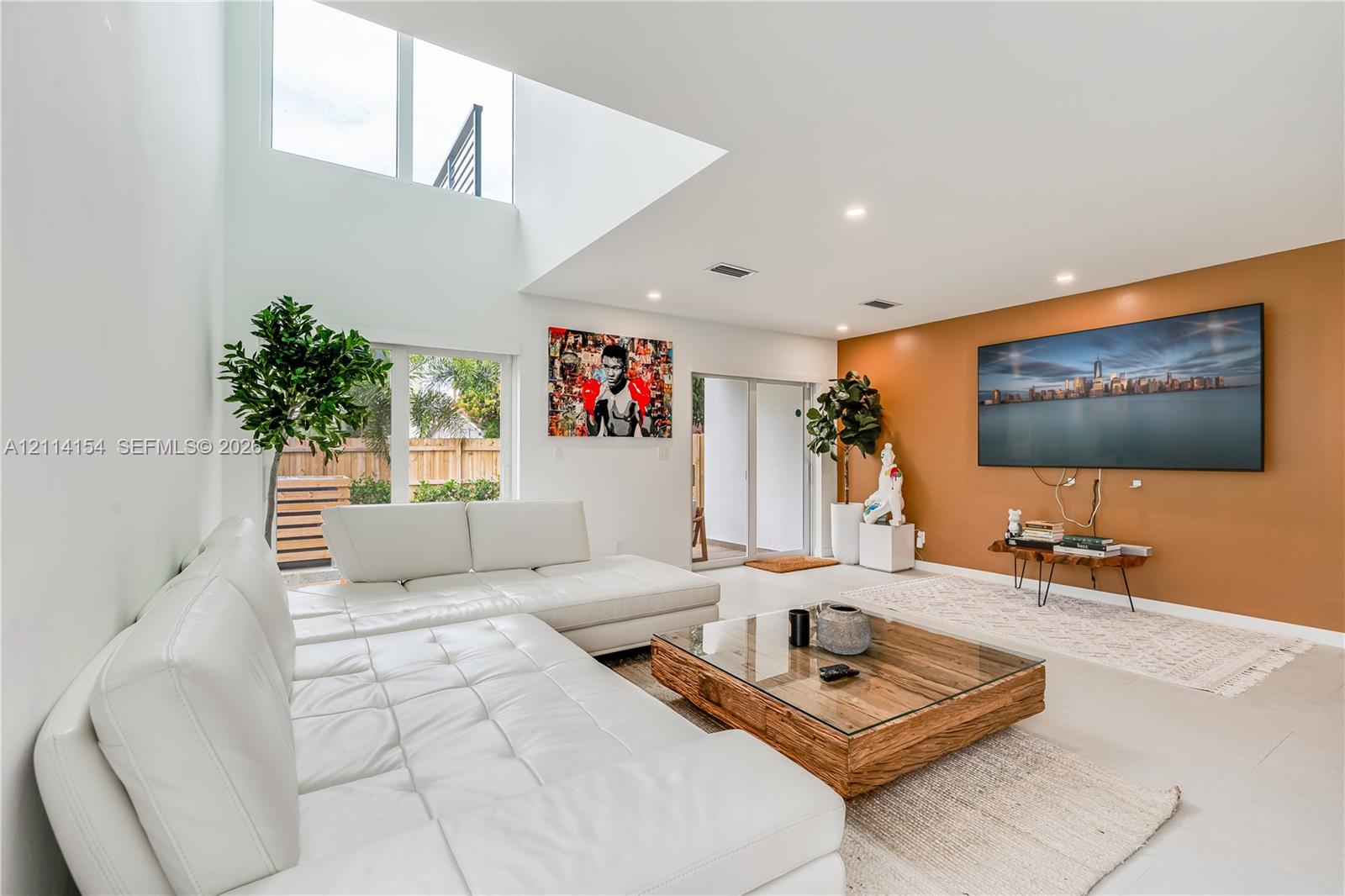 High-ceiling living area featuring double-height windows, recessed lighting, and large-format tile flooring