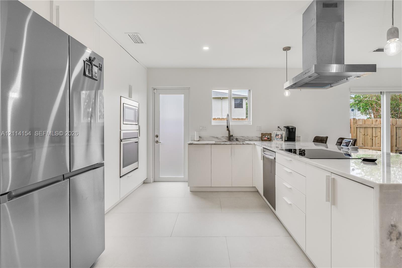 Modern kitchen featuring flat-panel cabinetry, stone countertops, stainless steel appliances, a chimney-style range hood, and large-format tile flooring