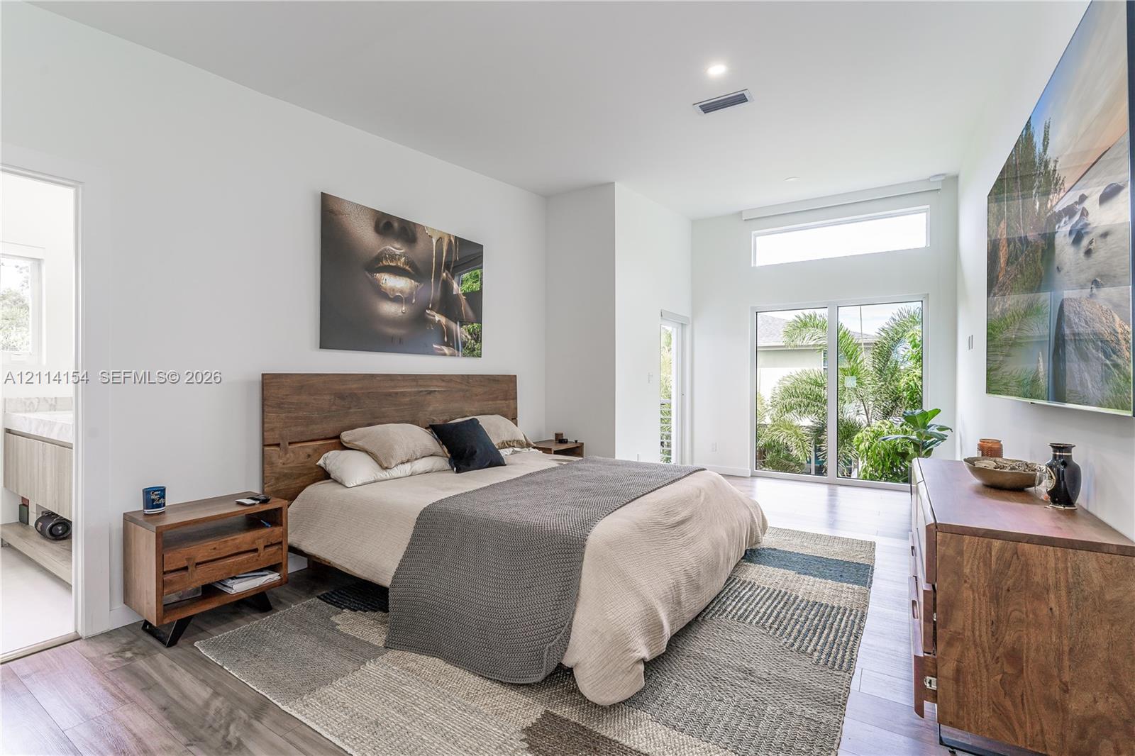 High ceilings with transom window, wood-finish flooring, and large sliding glass doors