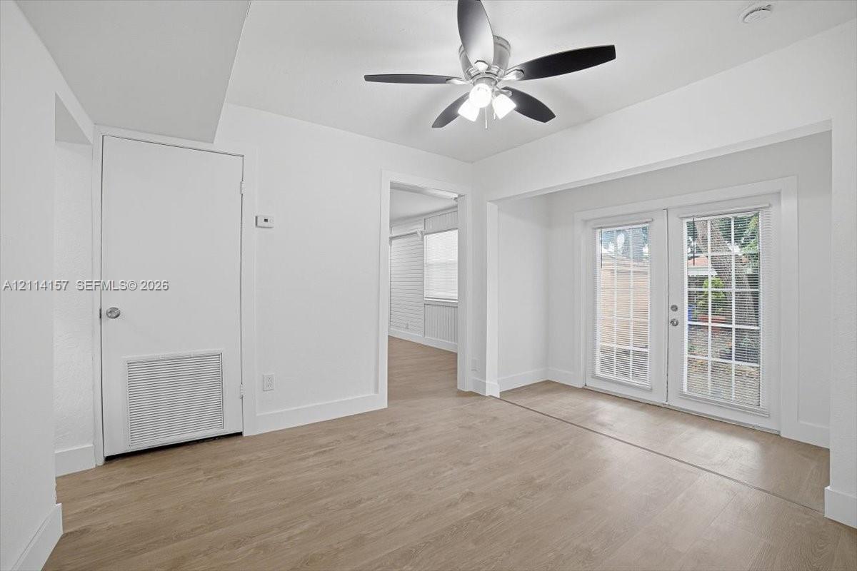 Interior space featuring wood-finish flooring, white walls, and a ceiling fan with integrated lighting