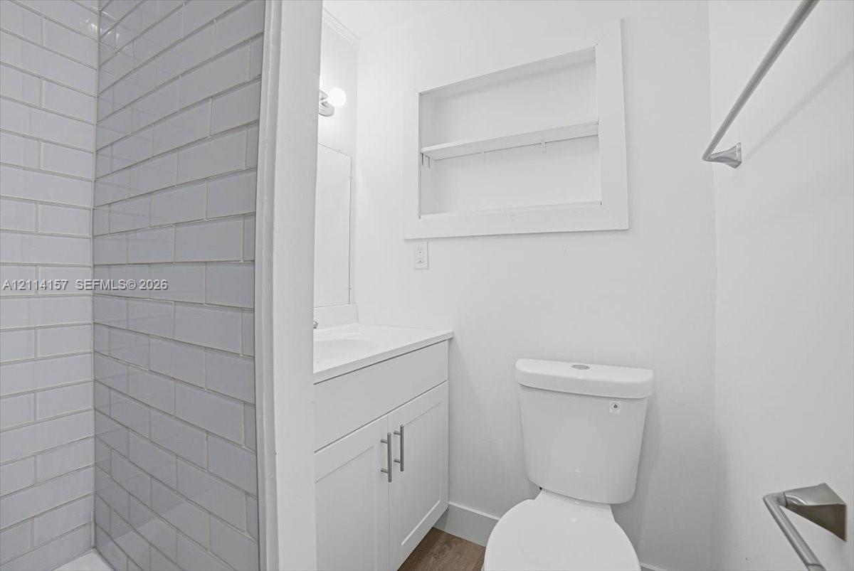 Bathroom featuring subway tile shower surround, white vanity with integrated basin, recessed wall niche, and polished chrome hardware