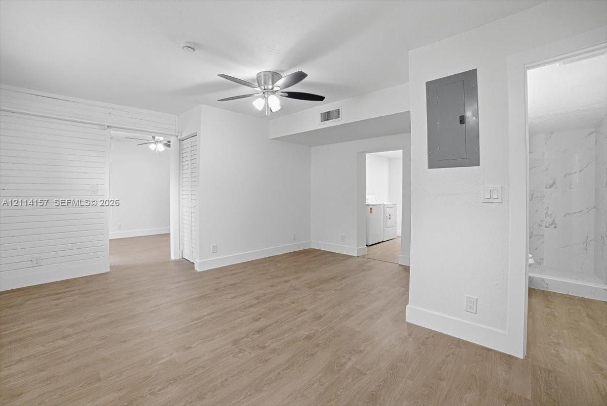 Wood-finish flooring, horizontal shiplap wall detail, ceiling fan with integrated lighting, and louvered closet doors