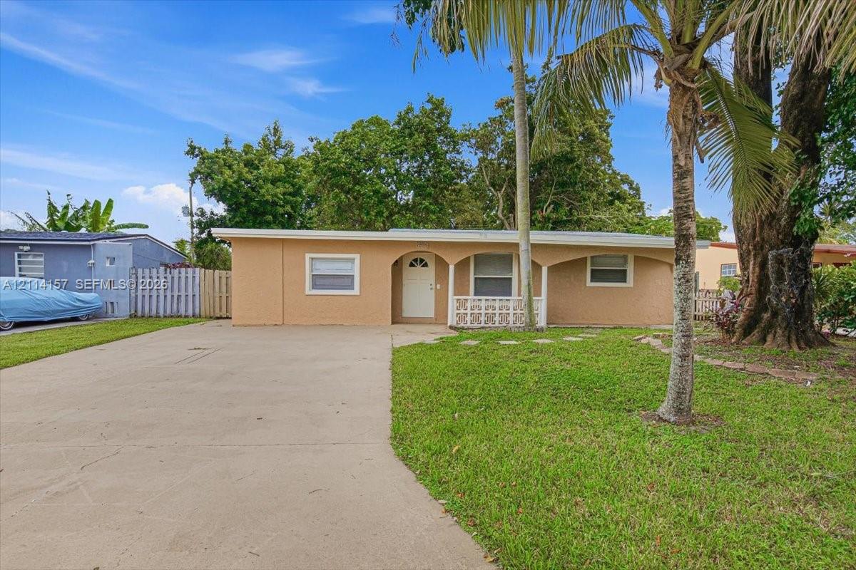 Single-story residence featuring a stucco exterior, concrete driveway, arched covered porch entry, decorative privacy screen, and mature landscaping