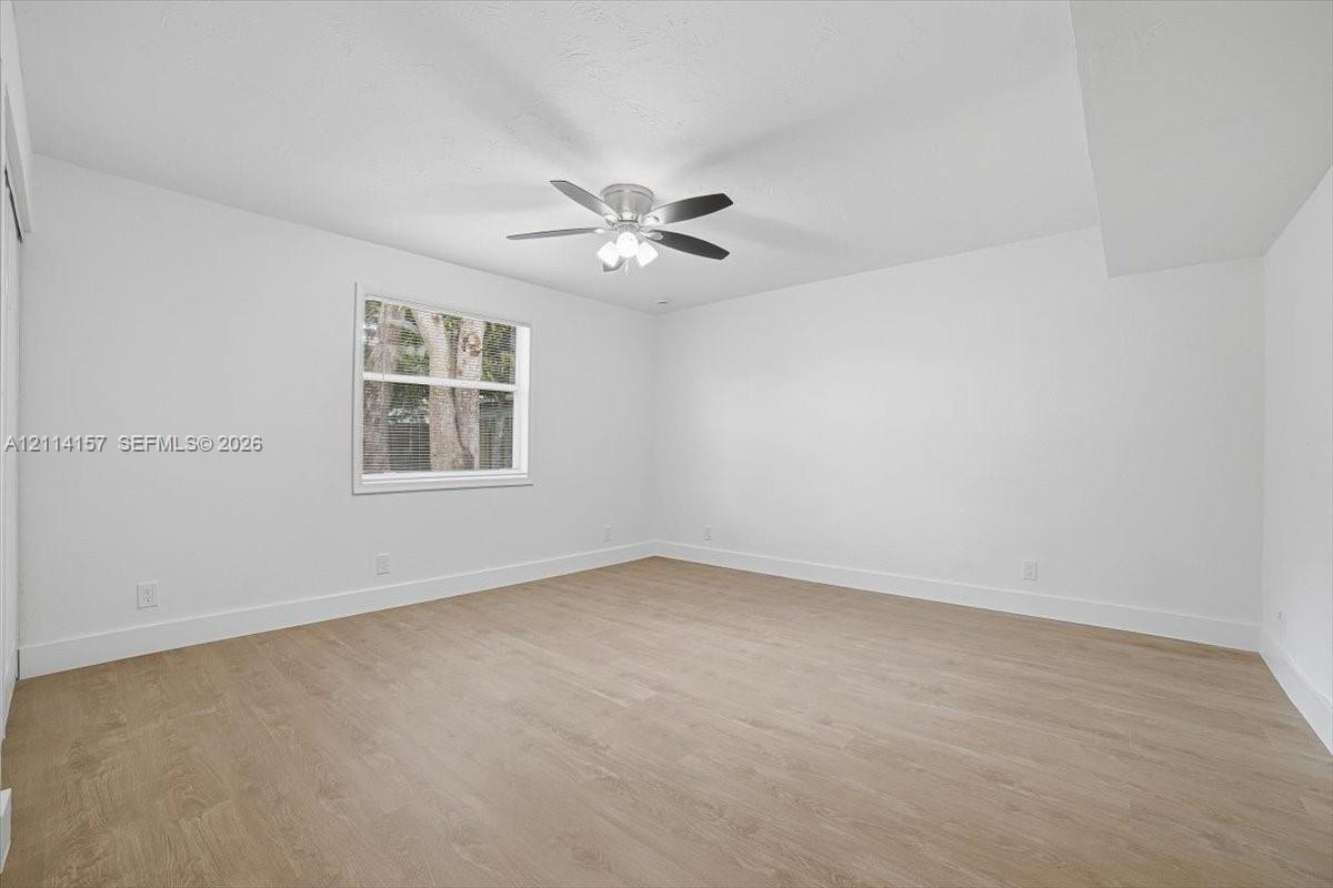 Bright room featuring wood-finish flooring, a neutral color palette, a single-hung window, and a multi-blade ceiling fan with integrated lighting