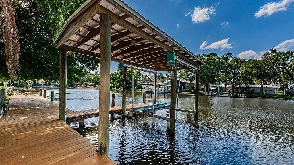Waterfront wooden dock featuring a covered boat slip with a mechanical lift