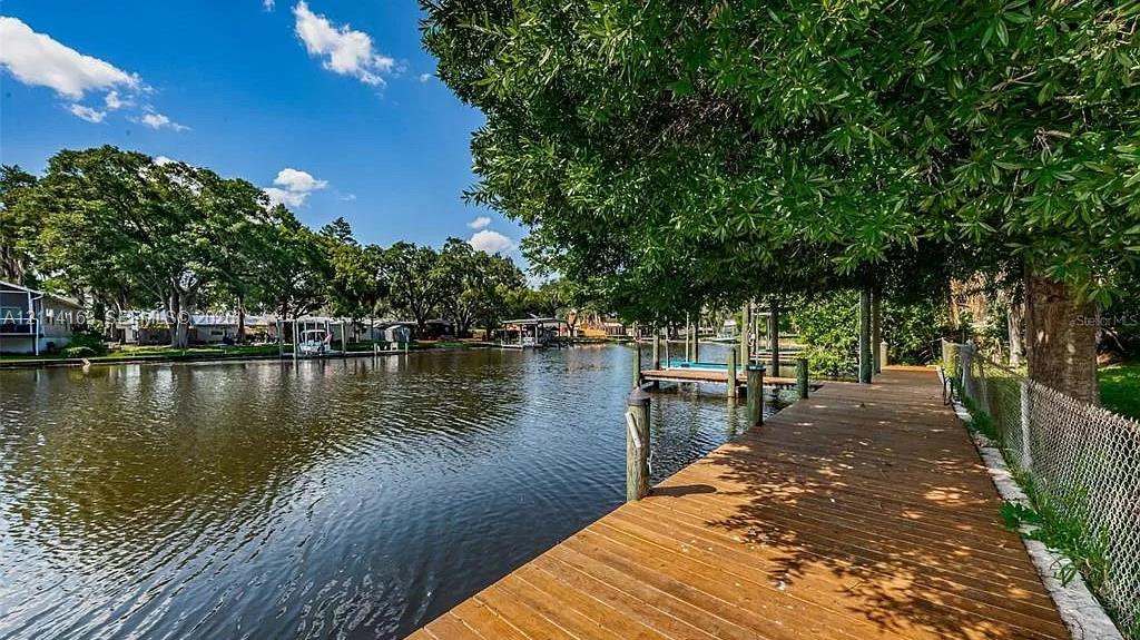 Waterfront property featuring a wood-plank dock, canal access, and mature canopy trees