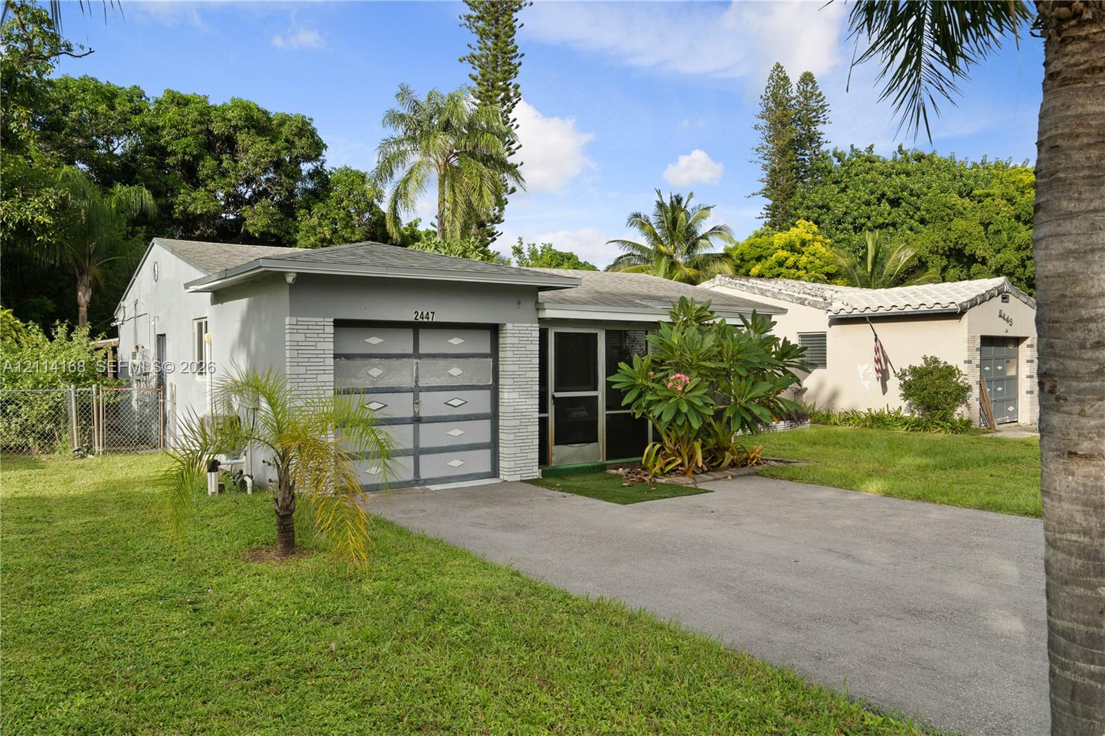 Single-story residence, textured exterior siding, and a paved driveway, surrounded by a lawn with mature trees and vegetation Single-story residence, textured exterior siding, and a paved driveway, surrounded by a lawn with mature trees and vegetation
