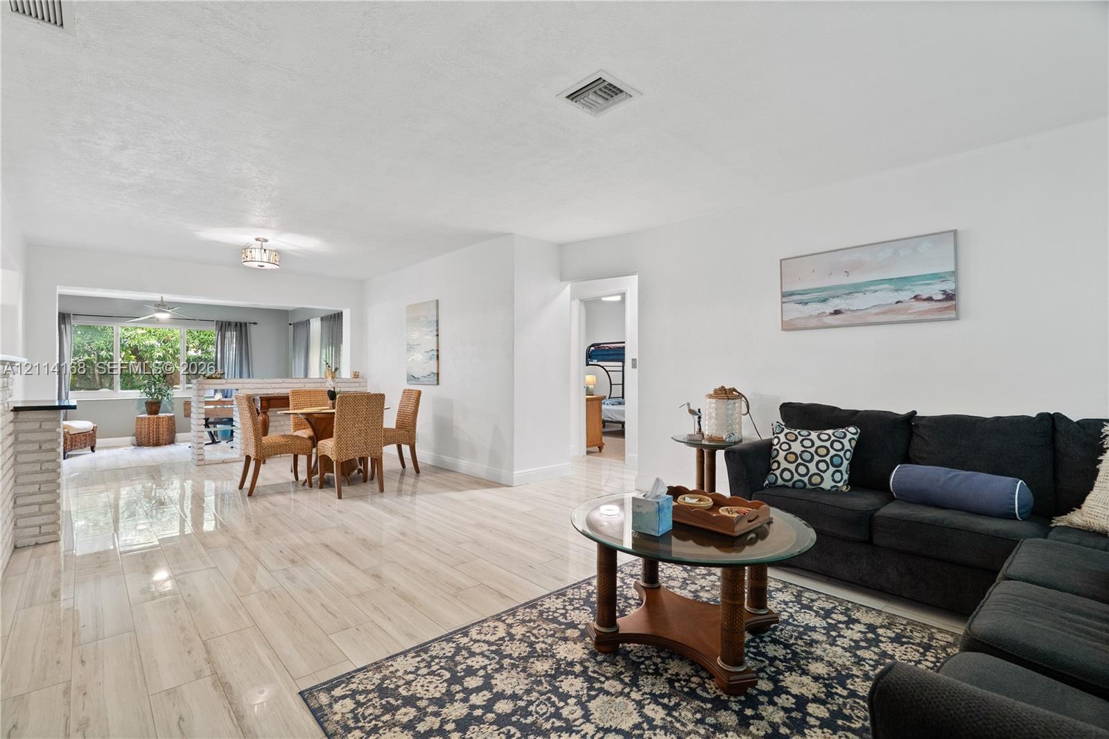 Open-concept interior featuring Italian Tile flooring, white walls, brick fireplace surround, and recessed ceiling lighting
