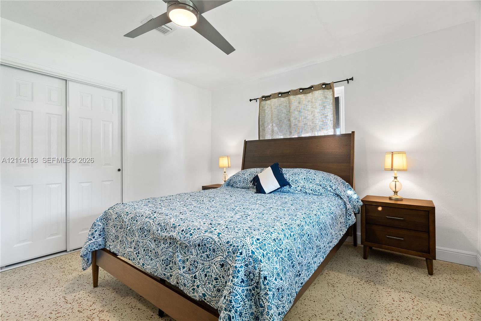 Room featuring polished terrazzo flooring, a ceiling fan with integrated lighting, and a closet with dual sliding paneled doors