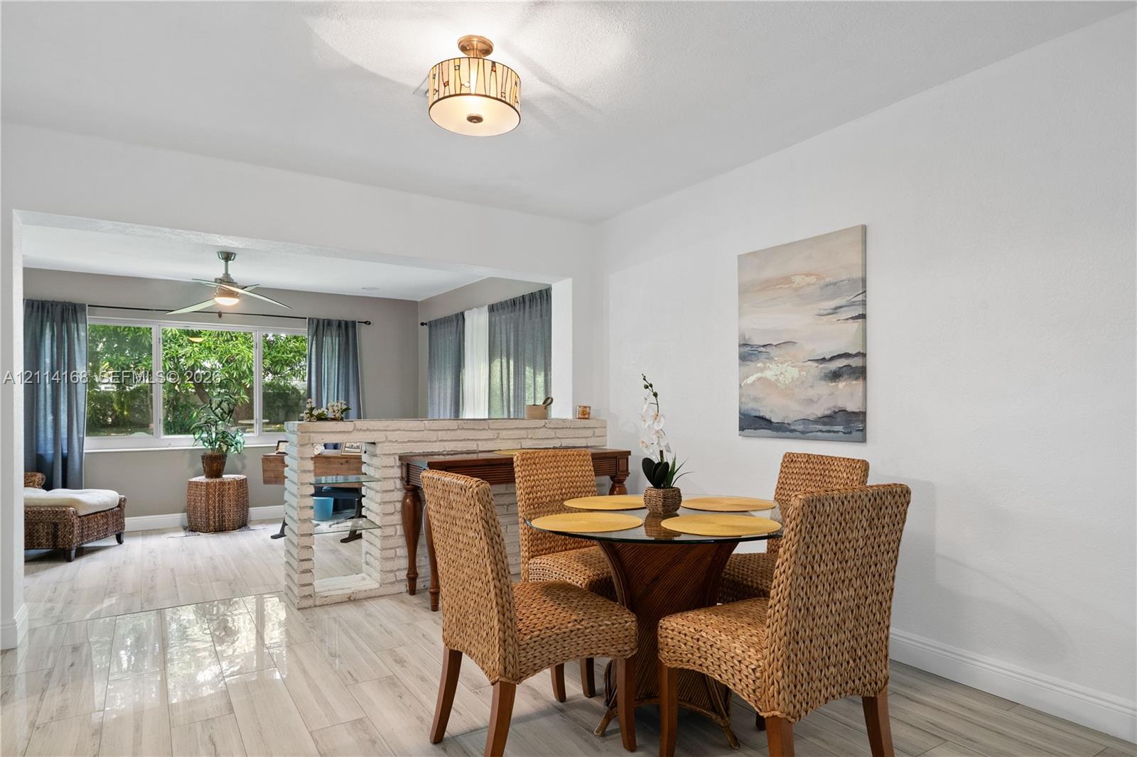 Italian Tile flooring throughout, low-profile brick partition wall, drum-style ceiling light fixture, ceiling fan, and large windows
