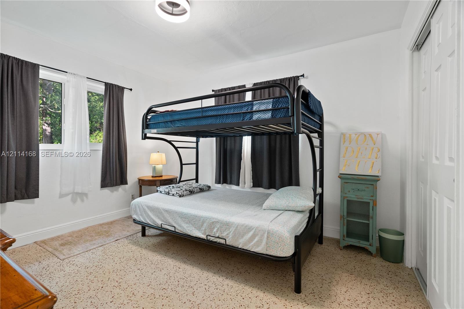2nd Bedroopm Neutral interior room featuring terrazzo flooring, dual-aspect windows, and a closet with sliding panel doors