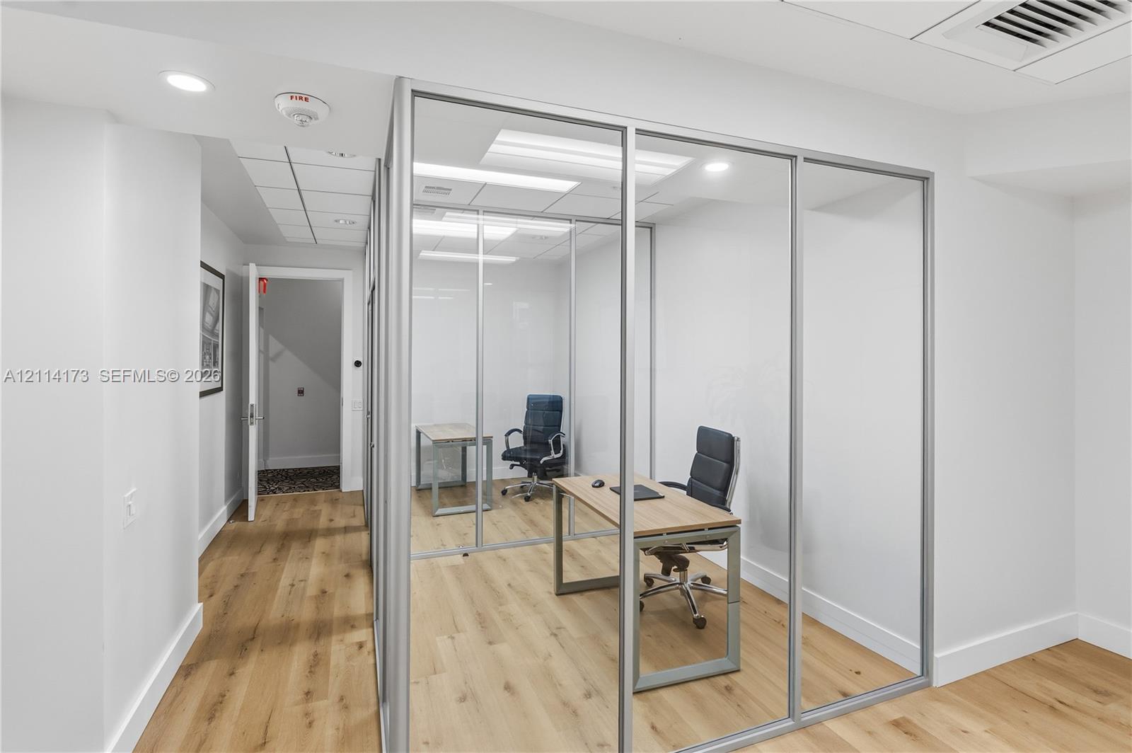 Enclosed office space featuring glass-panel walls, aluminum framing, recessed lighting, and wood-finish flooring