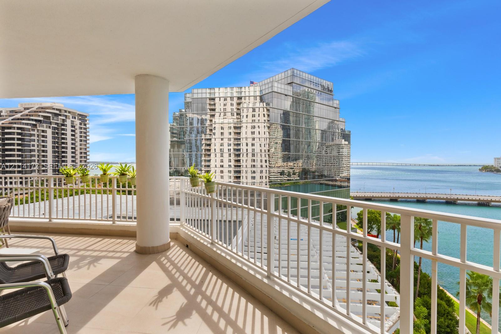 Covered balcony featuring tile flooring, a support column, and white metal railings with nautical and cityscape scenery