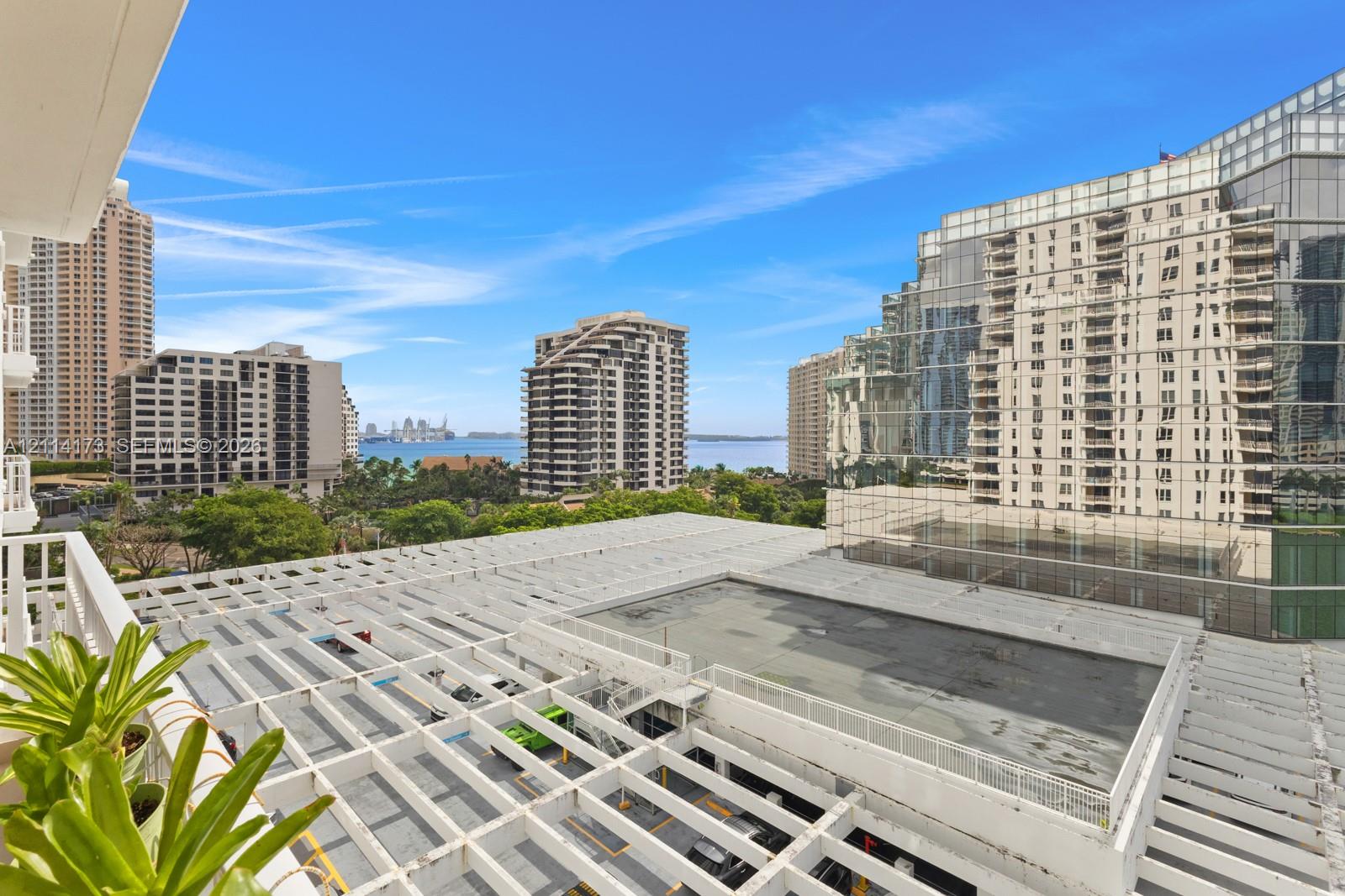 Private balcony featuring a structural white trellis overhead and a perspective of the surrounding urban skyline, waterfront, and marina