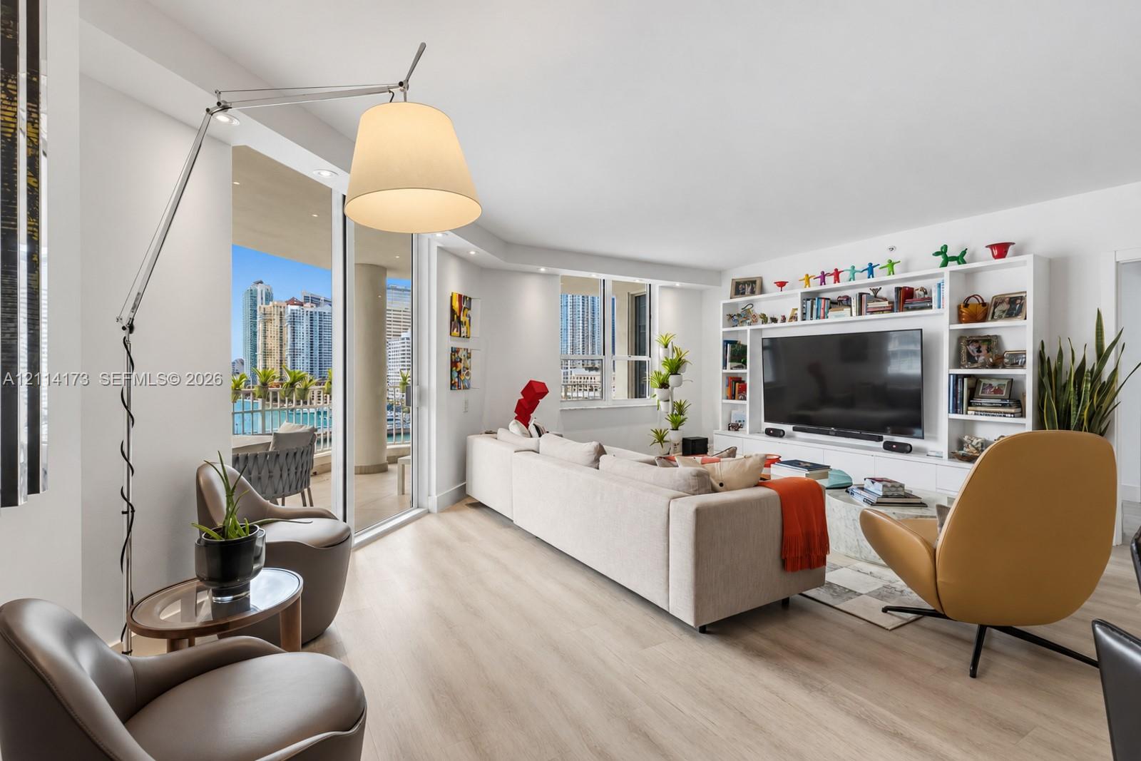 Open-concept living space featuring wood-finish flooring, floor-to-ceiling sliding glass doors, a large white built-in media center with integrated shelving, and recessed lighting