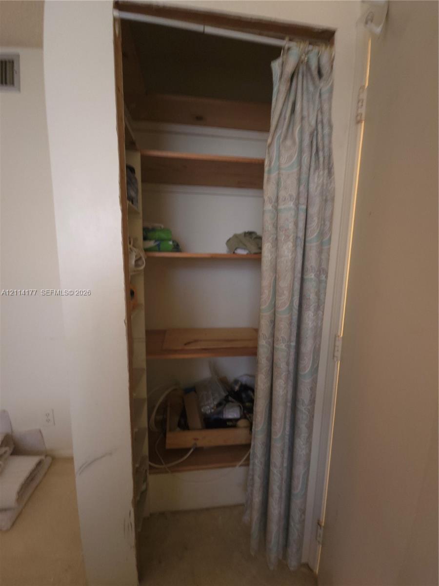 Storage alcove featuring built-in wooden shelving and tiered side shelving units