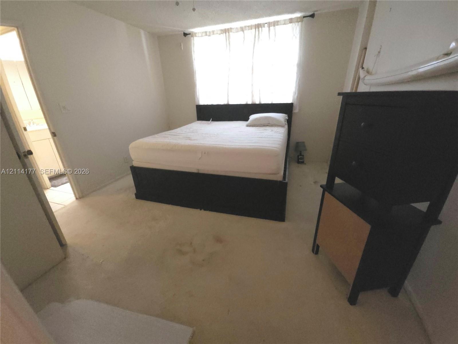 Neutral wall finishes, carpeting, and a window with hardware for window treatments
