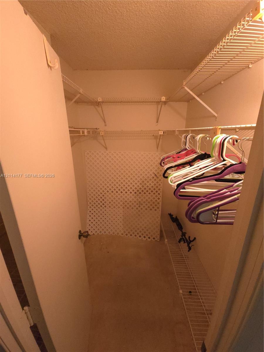 Walk-in closet featuring tiered white wire shelving and a floor-level lattice storage partition