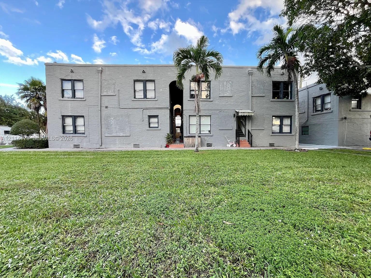 Multi-story masonry exterior with central arched entryway and expansive lawn