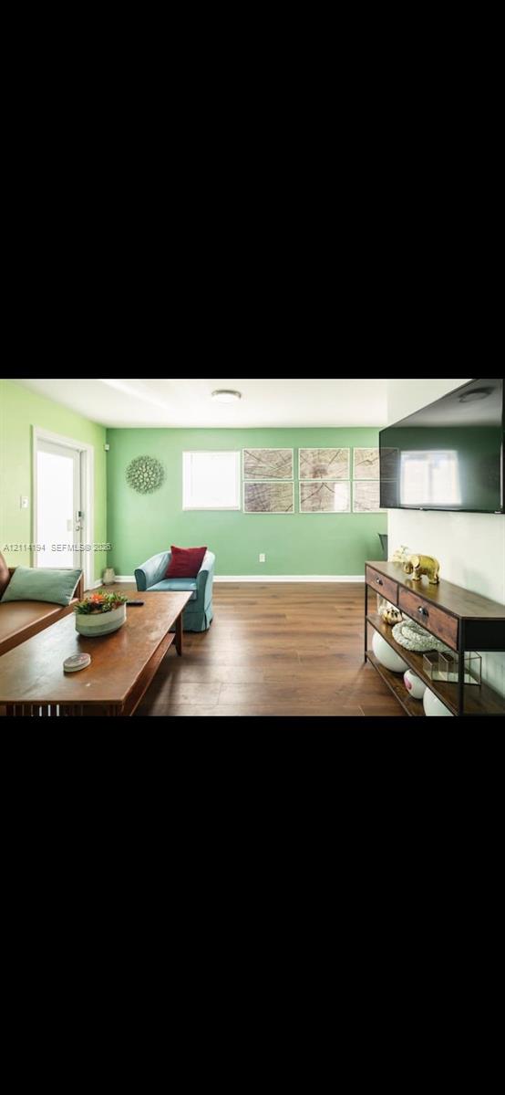 Living area featuring wood-finish flooring, recessed ceiling lighting, and a glass-paneled exterior door