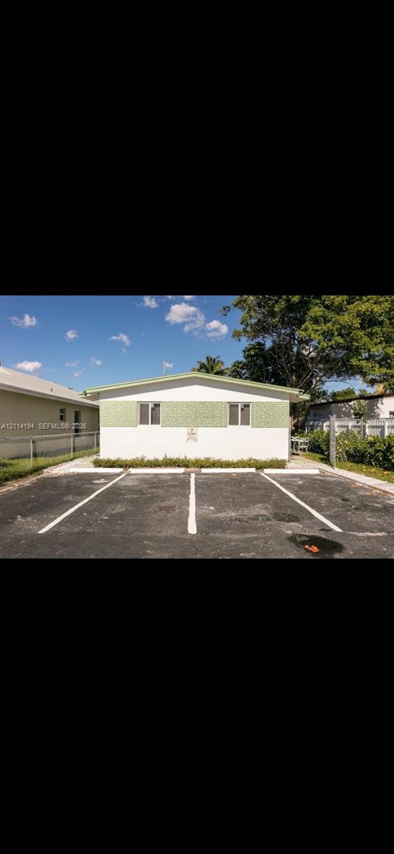 Exterior elevation featuring a gabled roofline, dual-tone stucco facade, and dedicated asphalt parking area