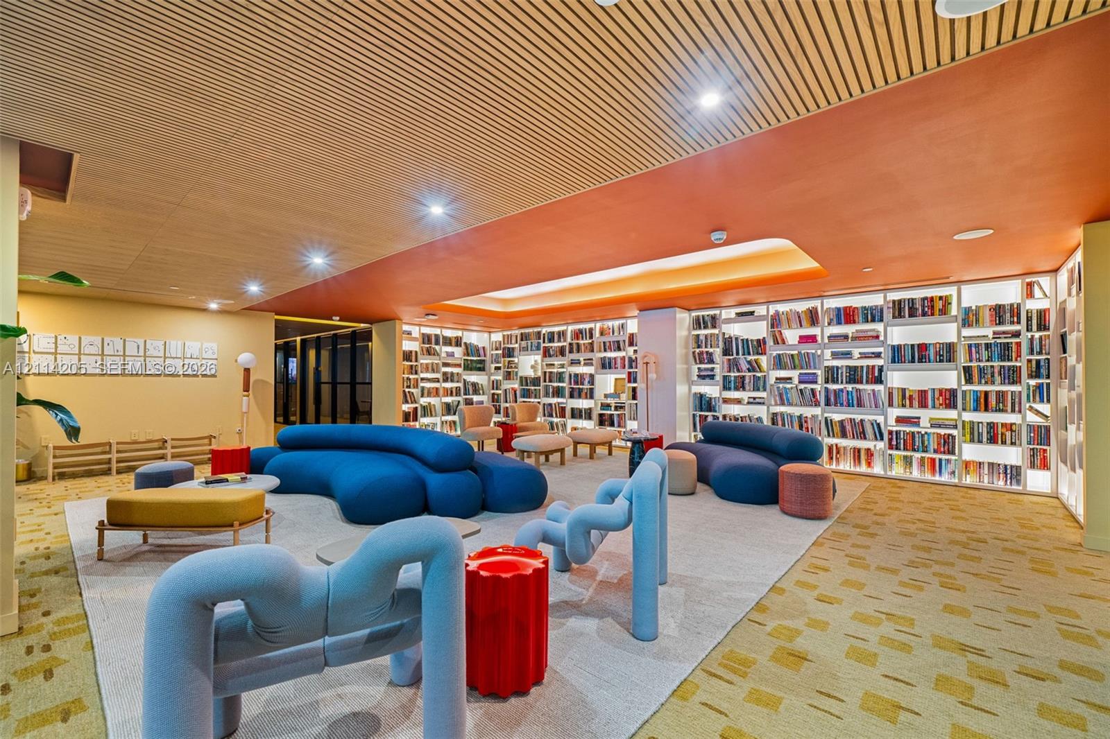 Custom floor-to-ceiling built-in library shelving with integrated LED illumination, wood-slat ceiling detailing, recessed lighting, and patterned carpeting
