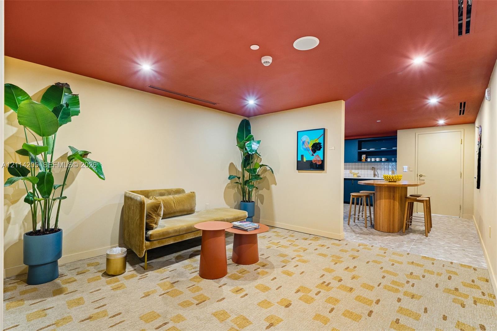 Interior space featuring a recessed ceiling with integrated lighting, patterned carpeting, and a kitchen area with built-in dark cabinetry and shelving - amenity