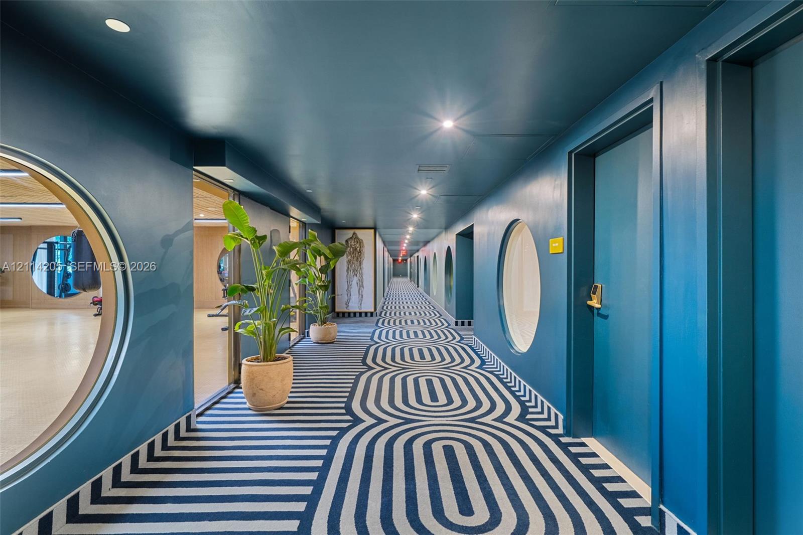 Hallway featuring circular window cutouts, recessed lighting, and patterned carpeting Hallway featuring circular window cutouts, recessed lighting, and patterned carpeting