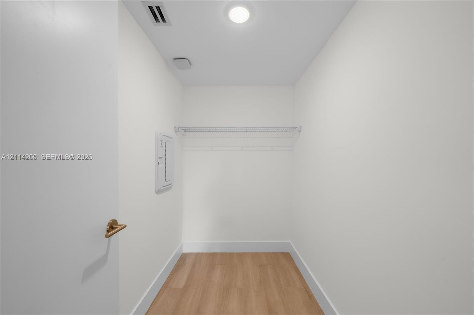 Enclosed storage space featuring wood-finish flooring, a white-coated wire shelf, and recessed ceiling lighting Enclosed storage space featuring wood-finish flooring, a white-coated wire shelf, and recessed ceiling lighting