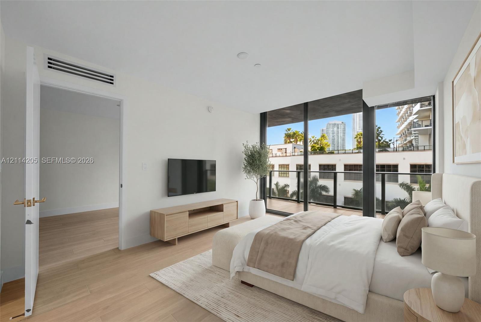 Floor-to-ceiling windows, wood-finish flooring, private balcony with black metal railing, and recessed ceiling lighting - staged Floor-to-ceiling windows, wood-finish flooring, private balcony with black metal railing, and recessed ceiling lighting - staged