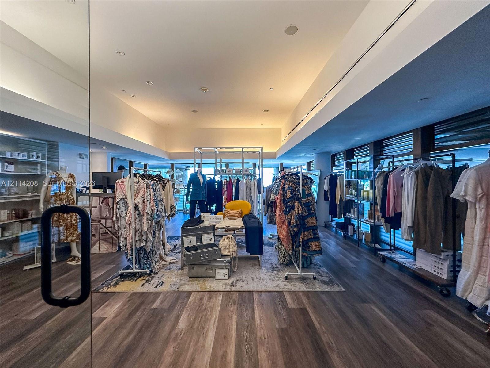 Expansive interior space featuring recessed lighting, wood-finish flooring, floor-to-ceiling glass storefront, and built-in wall shelving