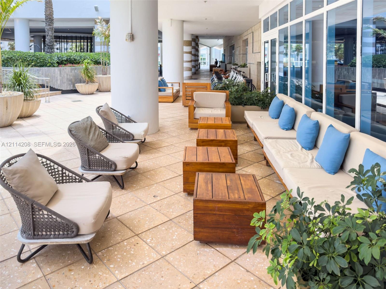 Covered outdoor terrace featuring light-toned stone tile flooring, structural pillars, and integrated planter boxes
