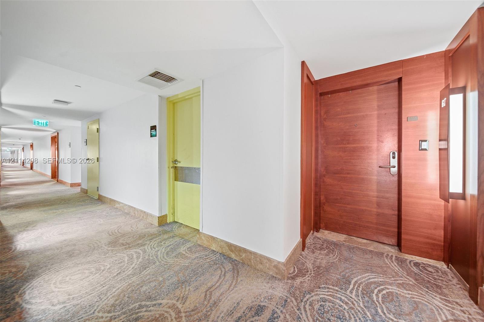 Hallway featuring pattern-carpeted flooring, solid wood-finish entry door with electronic deadbolt, smooth walls, and recessed lighting