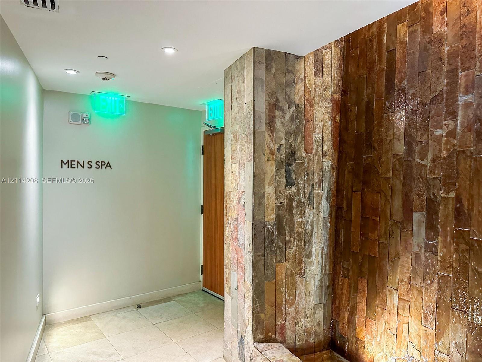 Floor-to-ceiling stone-clad wall accent, recessed ceiling lighting, and tile flooring