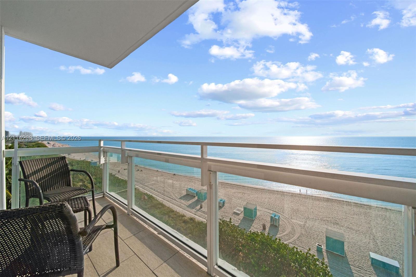 Private balcony featuring oversized tile flooring and a glass-panel railing overlooking the coastline