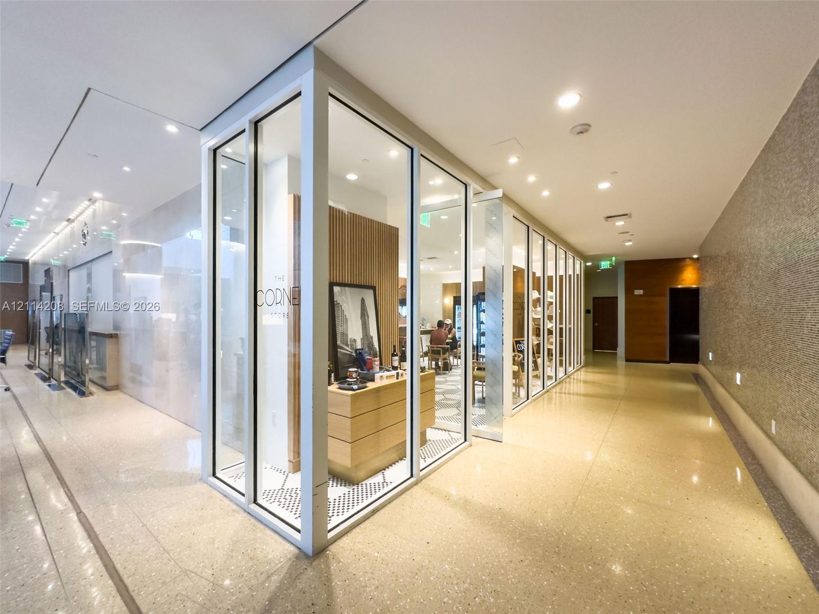 Floor-to-ceiling glass panel walls, polished stone flooring, recessed ceiling lighting, and wood-paneled feature walls