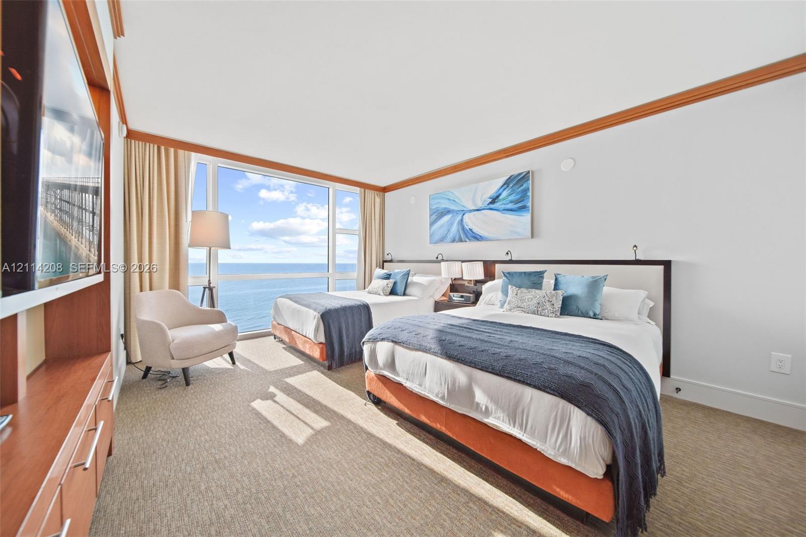 Floor-to-ceiling windows, ocean horizon, built-in wooden cabinetry, crown molding, and neutral wall-to-wall carpeting