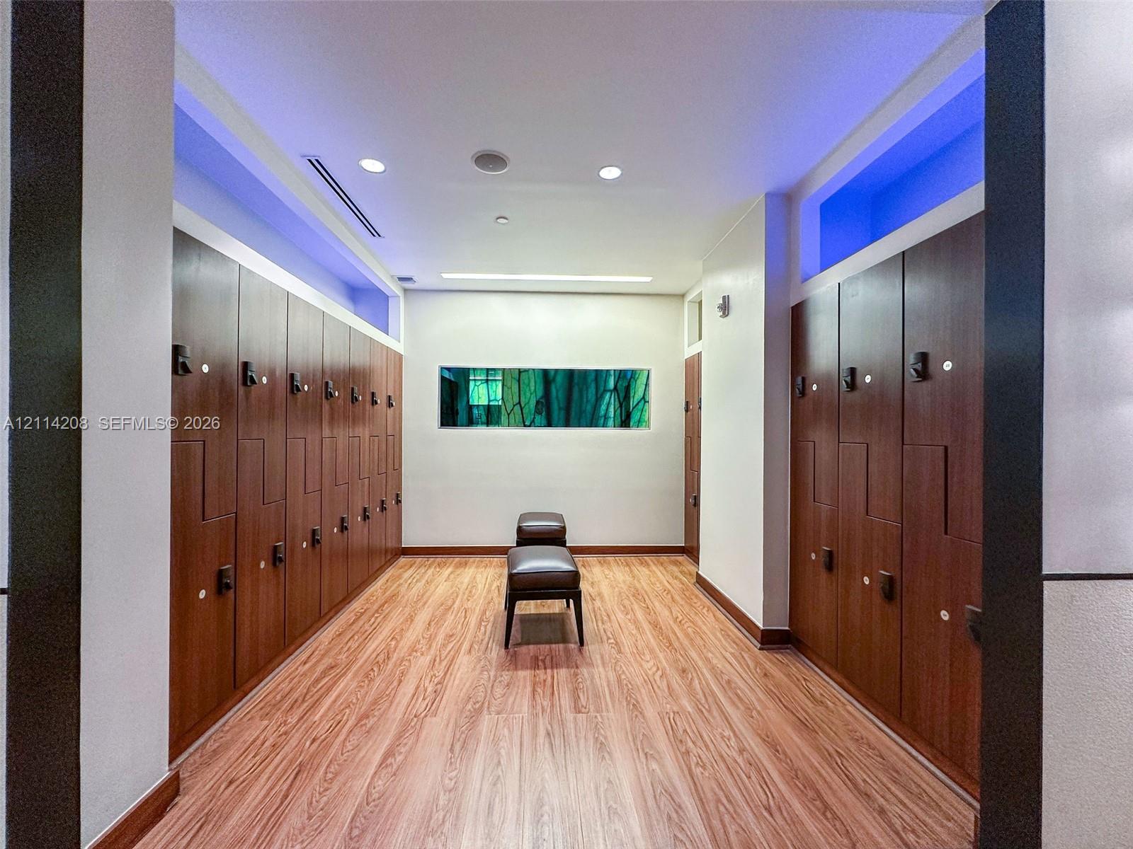 Rows of full-height wood-finish storage lockers, wood-finish flooring, recessed ceiling lighting, and a horizontal rectangular clerestory window