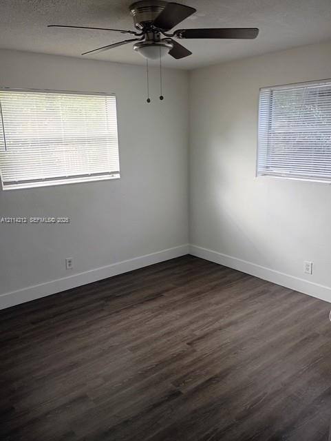 Room featuring wood-finish flooring, a ceiling fan with integrated lighting, and dual windows with horizontal blinds