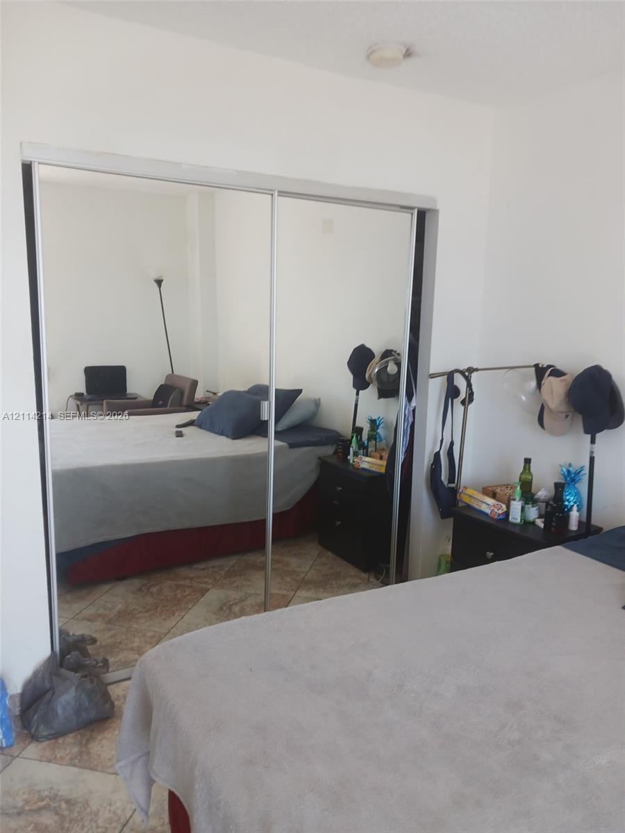 Sliding bypass closet doors with floor-to-ceiling mirrored panels and stone-finish tile flooring