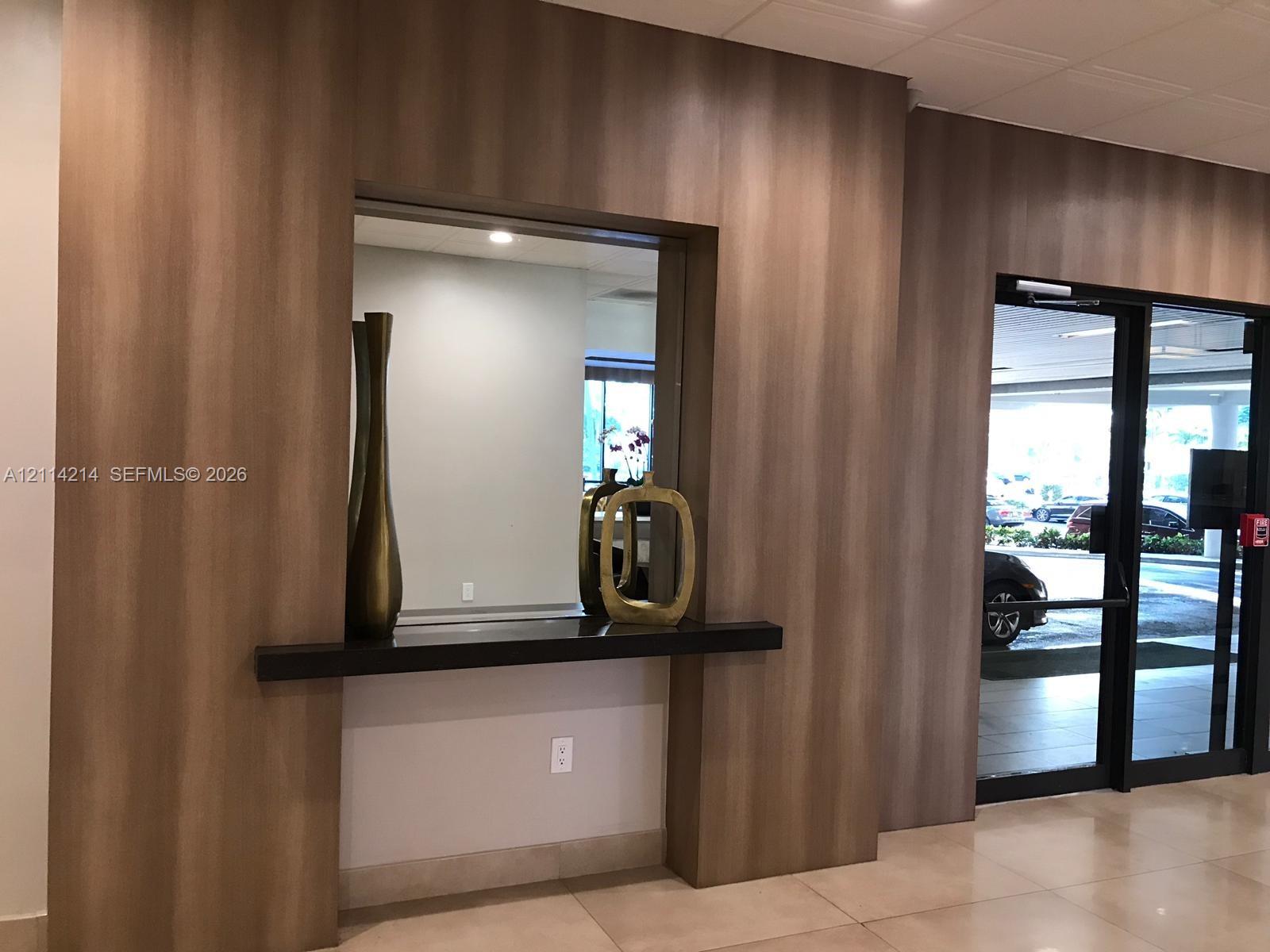 Wood-finish paneling, built-in shelving, glass-paned double entrance door, and tile flooring