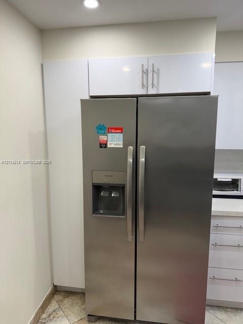 Stainless steel side-by-side refrigerator, gloss-finish white cabinetry, and recessed lighting
