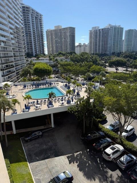 Elevated perspective featuring an outdoor swimming pool, paved surface parking, and mature palm trees