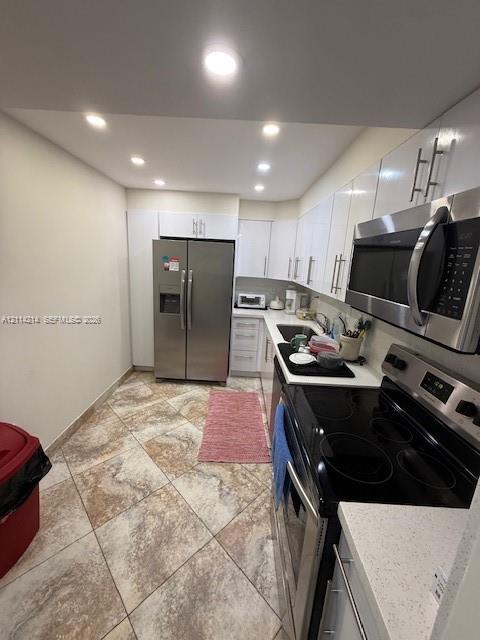 Kitchen featuring white cabinetry, stone-finish countertops, stainless steel appliances, and tile flooring