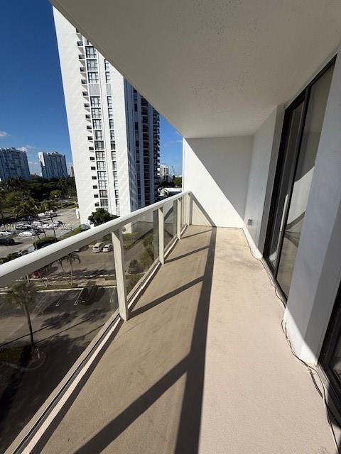 Private balcony featuring a glass-panel railing, concrete flooring, and a covered ceiling